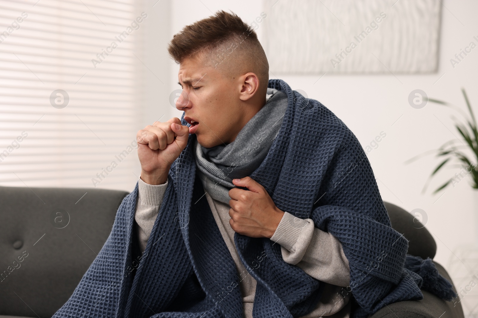 Photo of Cold symptom. Young man coughing at home