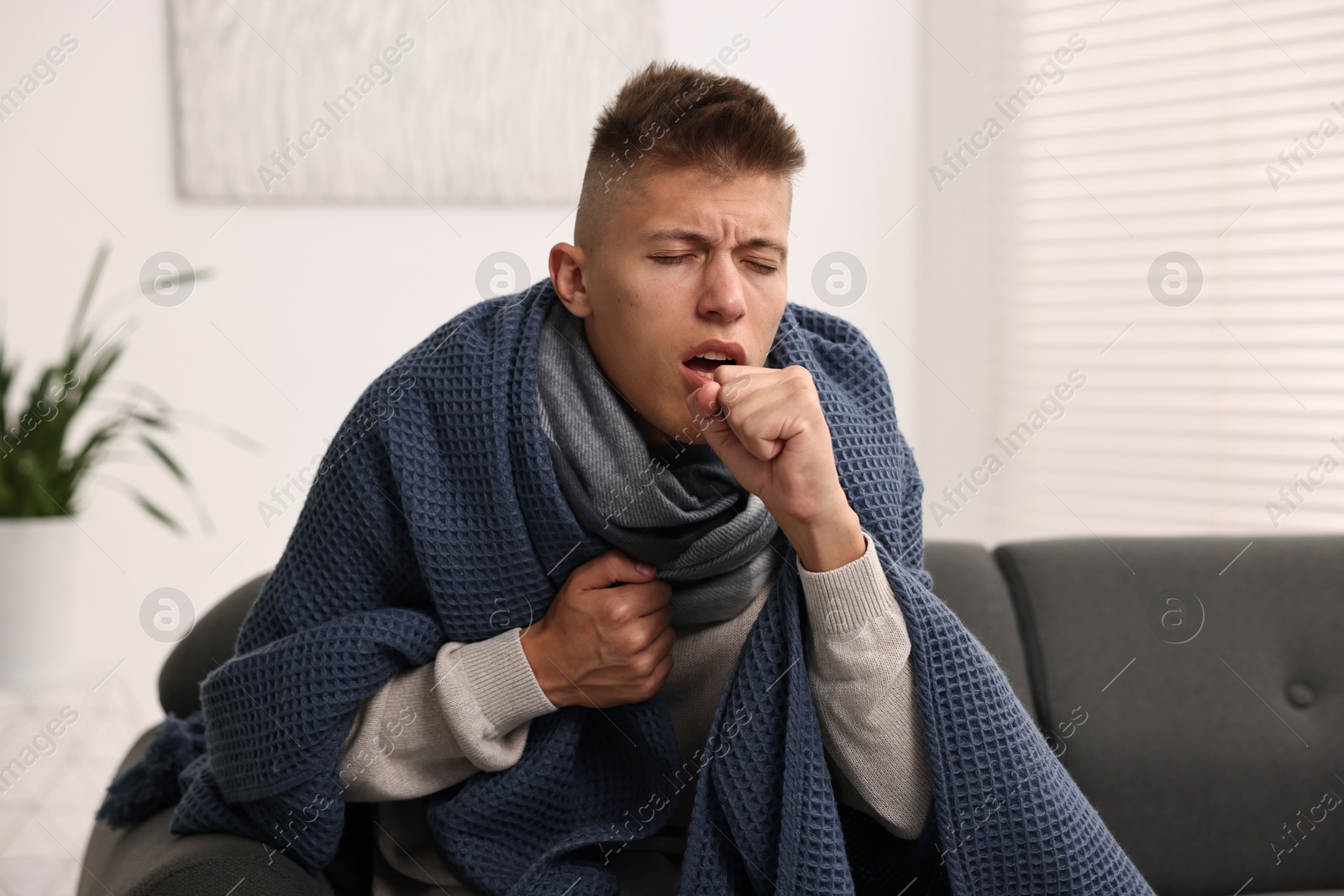 Photo of Cold symptom. Young man coughing at home