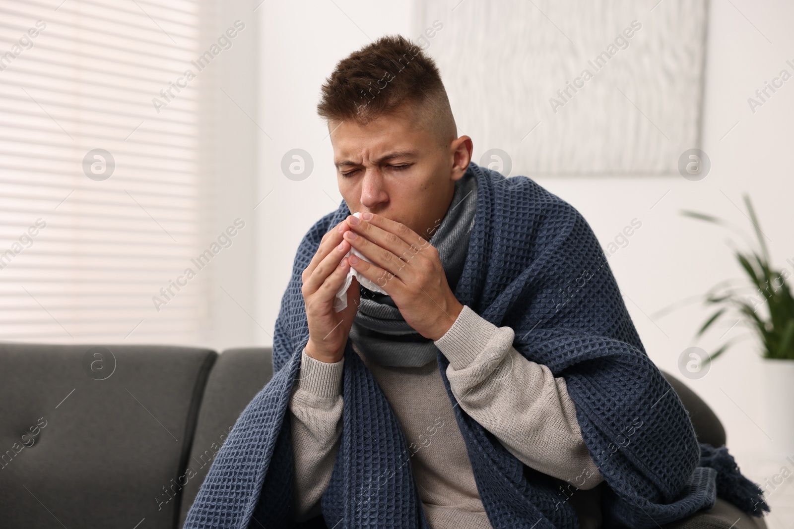 Photo of Cold symptom. Young man with runny nose at home