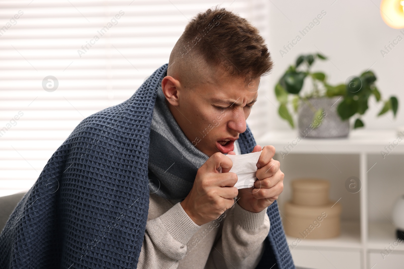 Photo of Cold symptom. Young man coughing at home