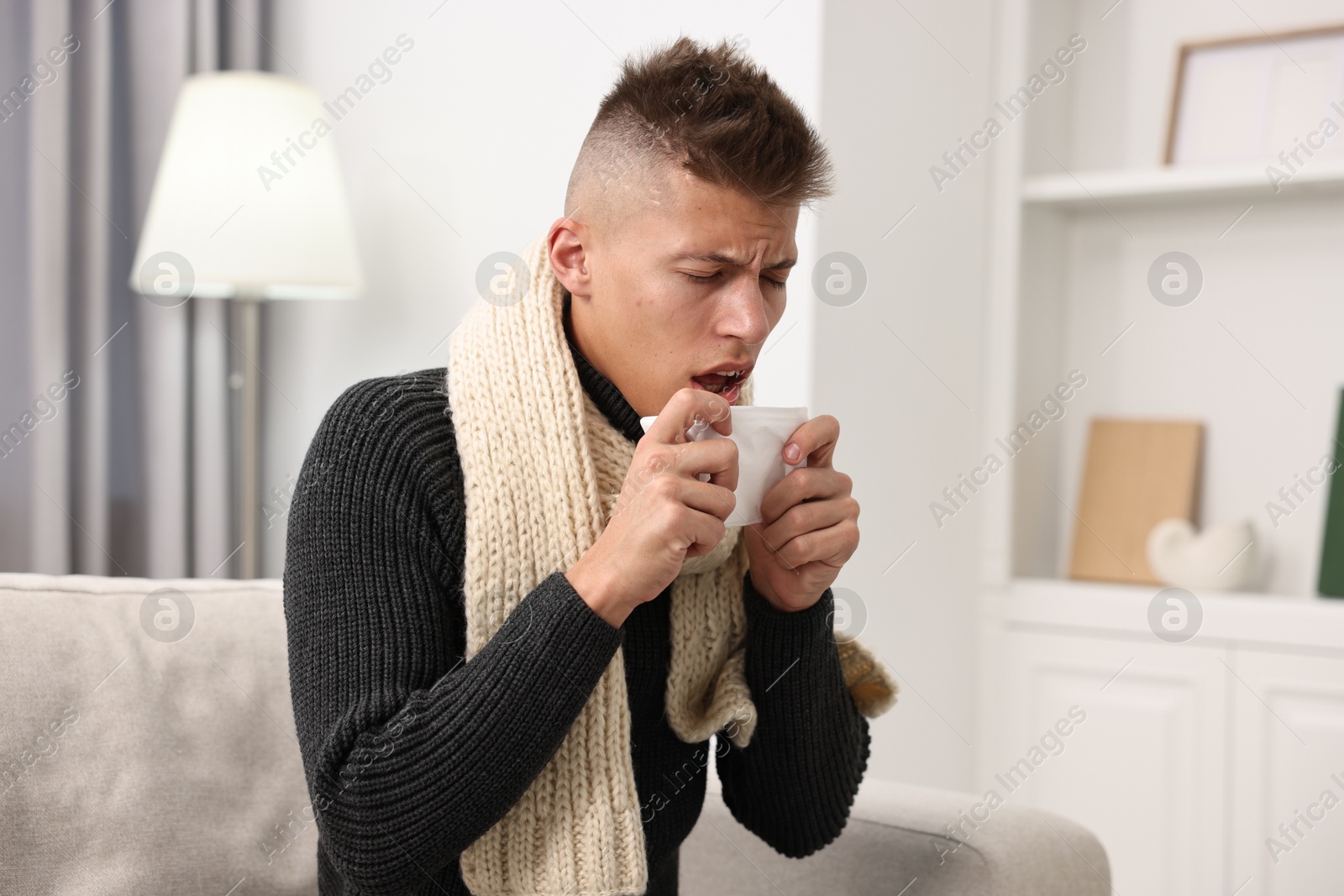 Photo of Cold symptom. Young man coughing at home