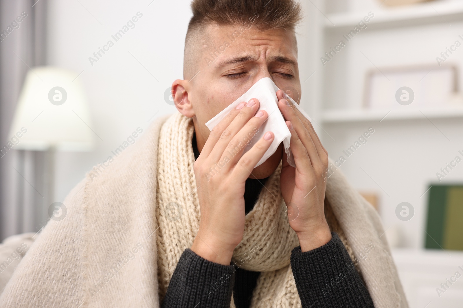 Photo of Cold symptom. Young man with runny nose at home