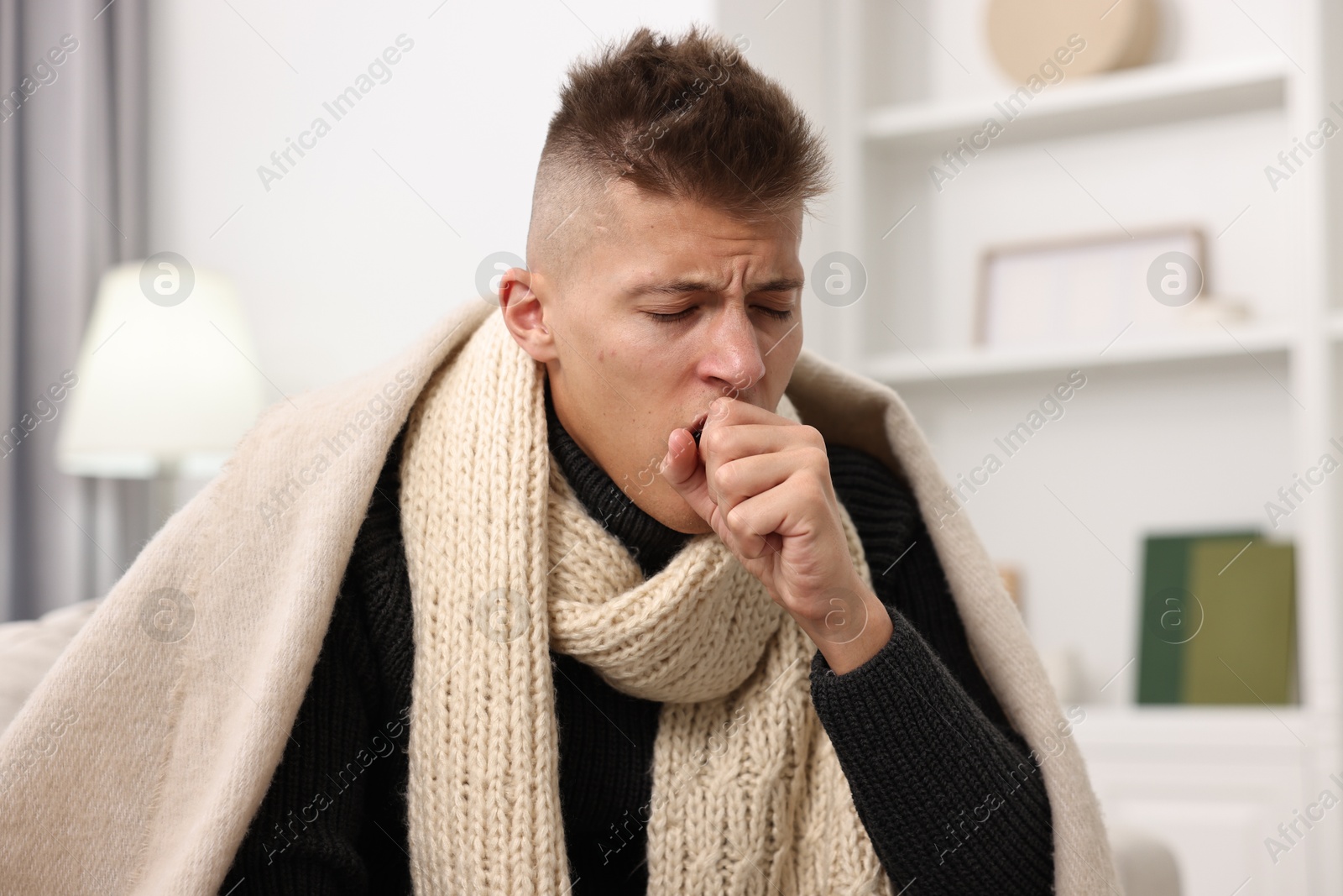 Photo of Cold symptom. Young man coughing at home