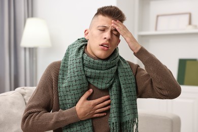 Photo of Cold symptom. Young man suffering from fever at home