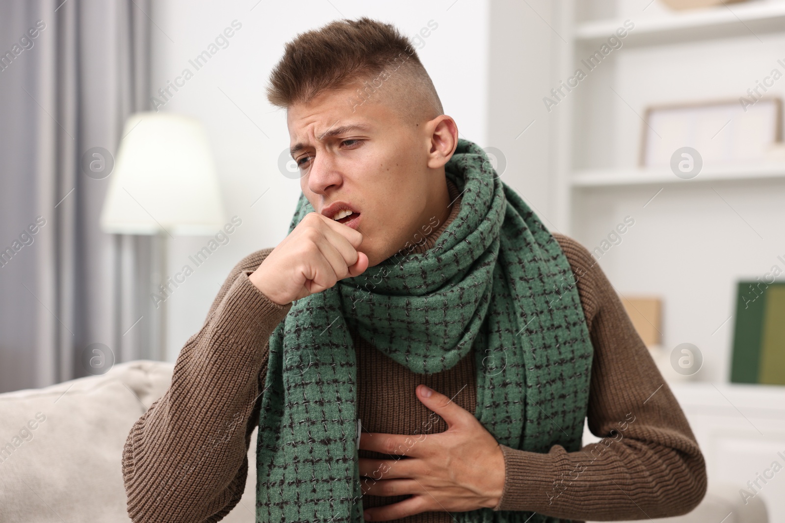 Photo of Cold symptom. Young man coughing at home