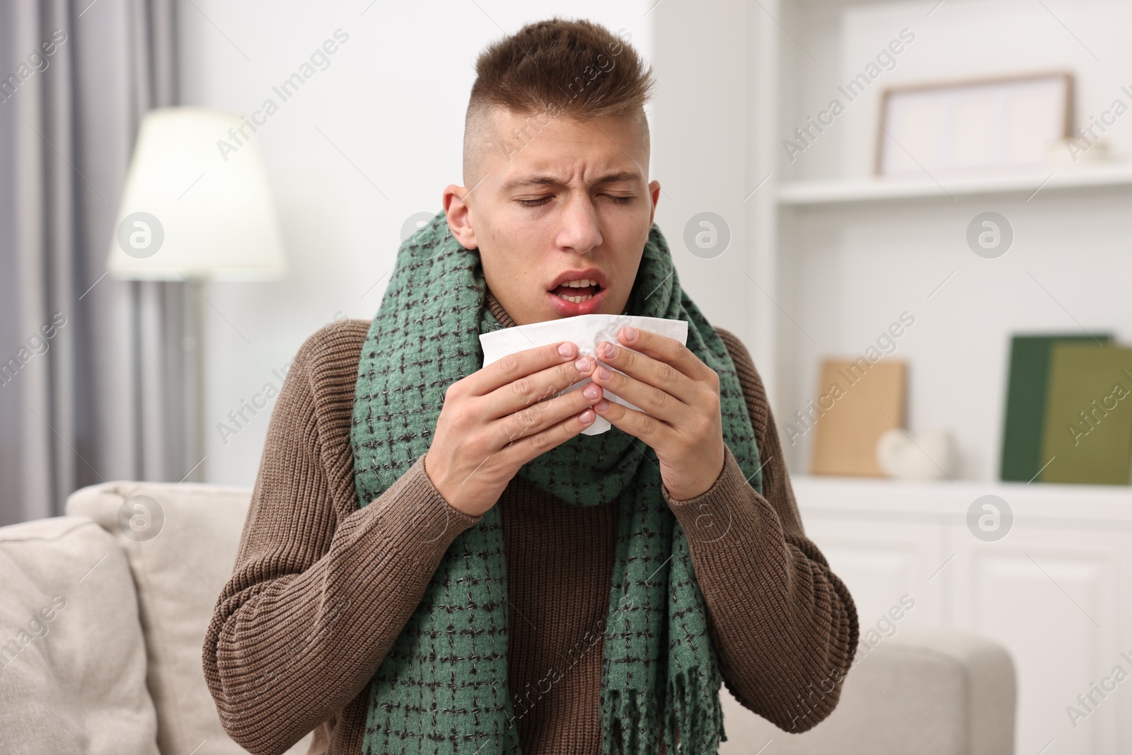 Photo of Cold symptom. Young man with runny nose at home