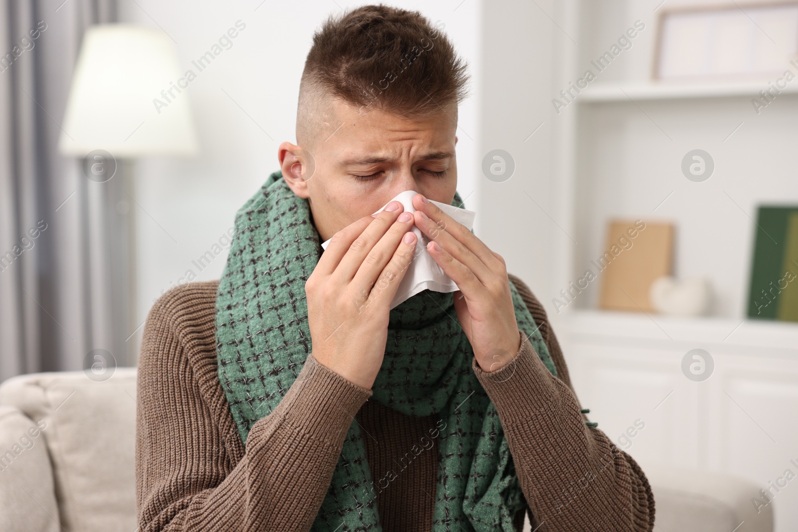 Photo of Cold symptom. Young man with runny nose at home