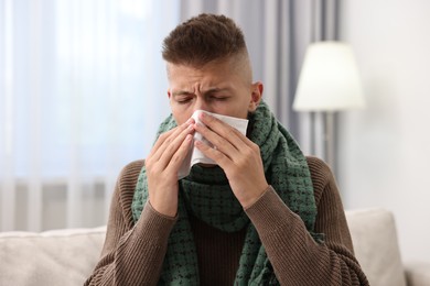 Photo of Cold symptom. Young man with runny nose at home