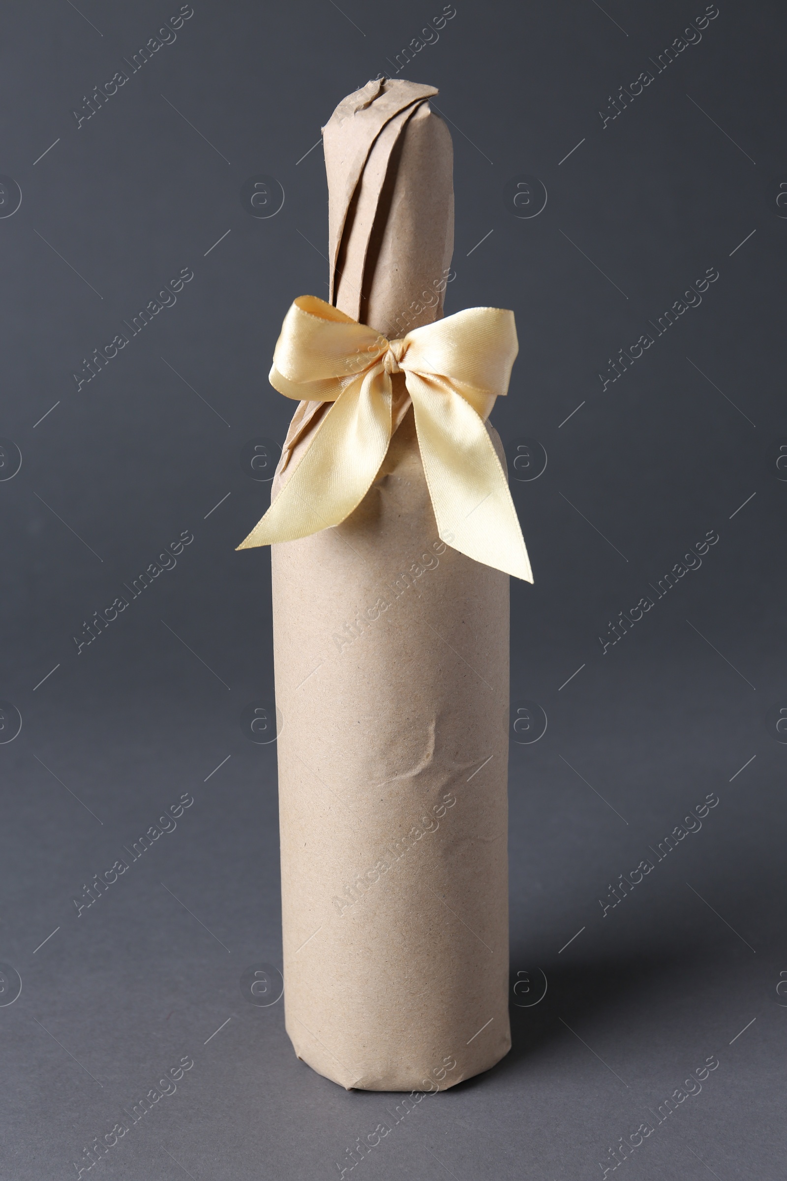 Photo of Wine packed bottle with ribbon on grey background