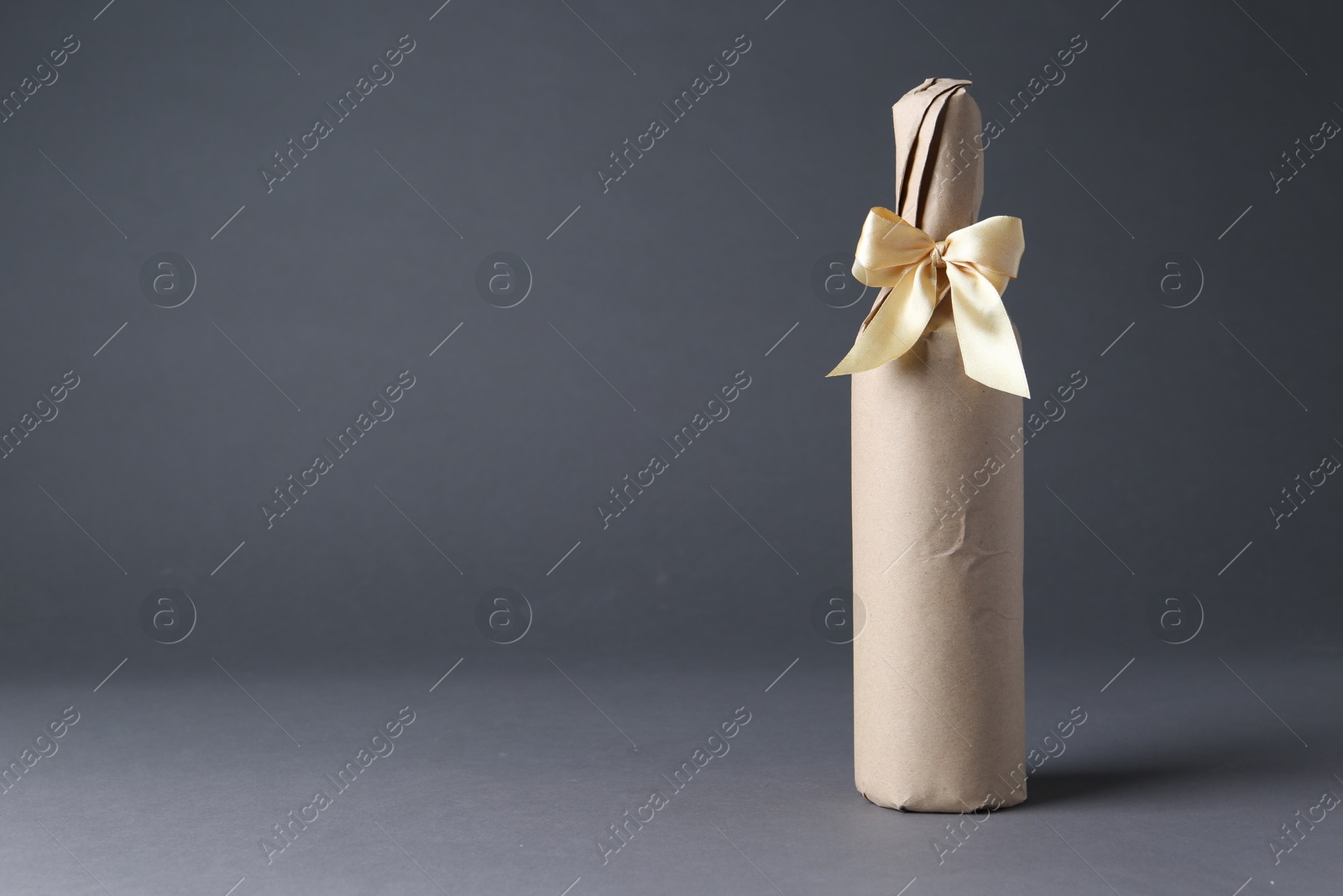 Photo of Wine packed bottle with ribbon on grey background, space for text