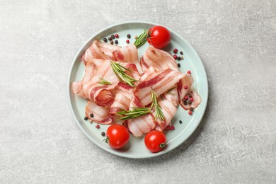 Photo of Slices of raw bacon, spices and tomatoes on light grey table, top view