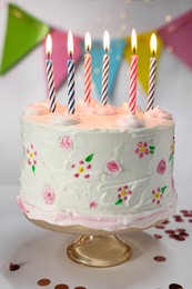 Tasty Birthday cake with burning candles and confetti on white table