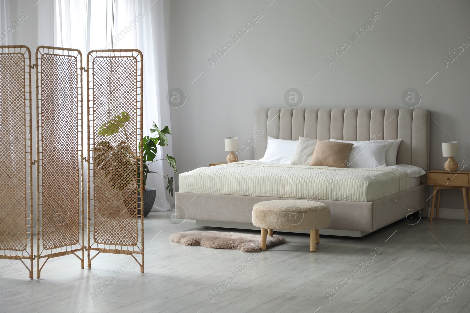 Photo of Folding screen and comfortable bed in bedroom. Interior design