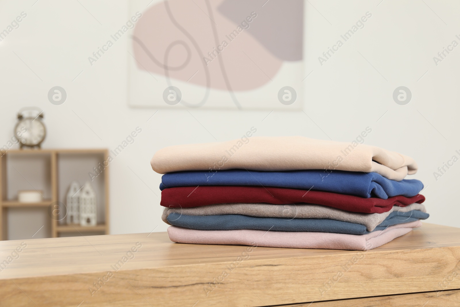 Photo of Stack of clothes on wooden chest of drawers indoors, space for text