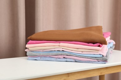 Stack of clothes on white table indoors