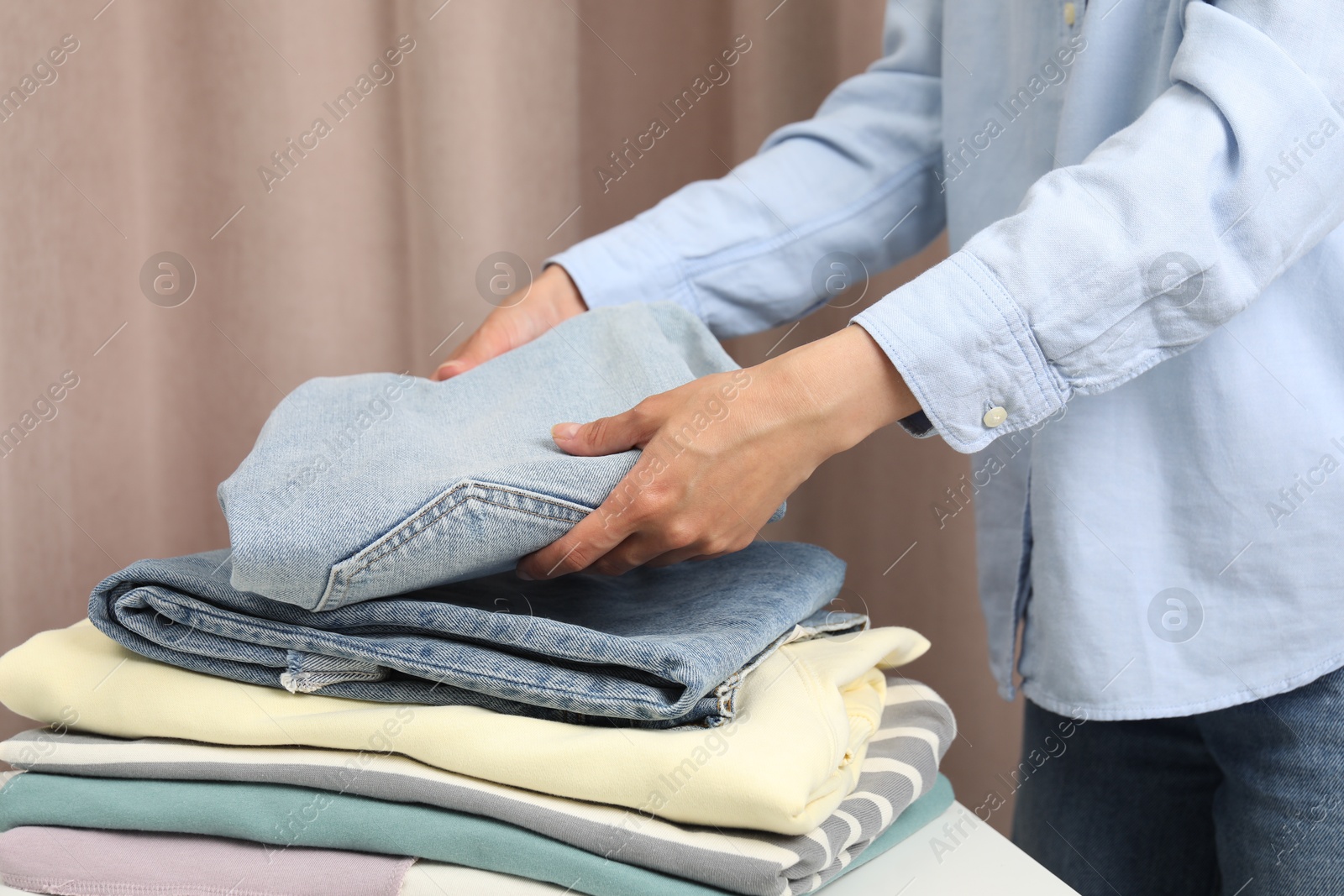 Photo of Woman folding clothes at table indoors, closeup