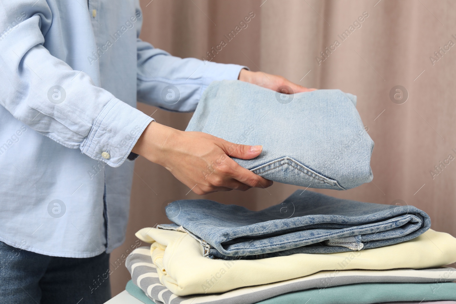 Photo of Woman folding clothes at table indoors, closeup