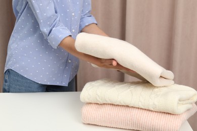 Woman folding clothes at white table indoors, closeup