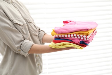 Woman with stack of clean clothes indoors, closeup