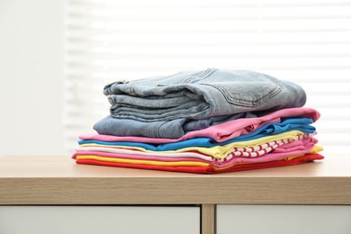 Stack of clean clothes on wooden dresser indoors