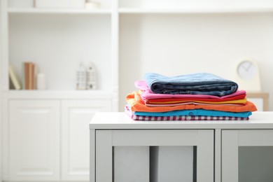 Photo of Stack of clean clothes on white dresser indoors