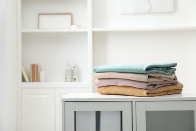 Photo of Stack of clean clothes on white dresser indoors