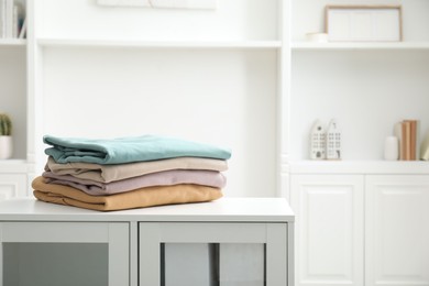 Photo of Stack of clean clothes on white dresser indoors