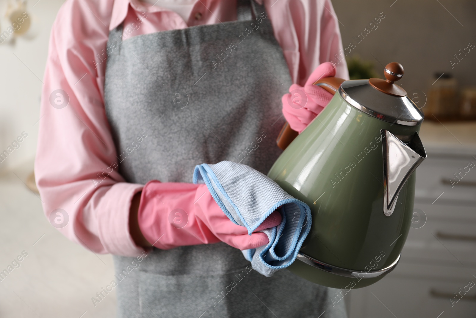 Photo of Woman wiping kettle with rag in kitchen, closeup