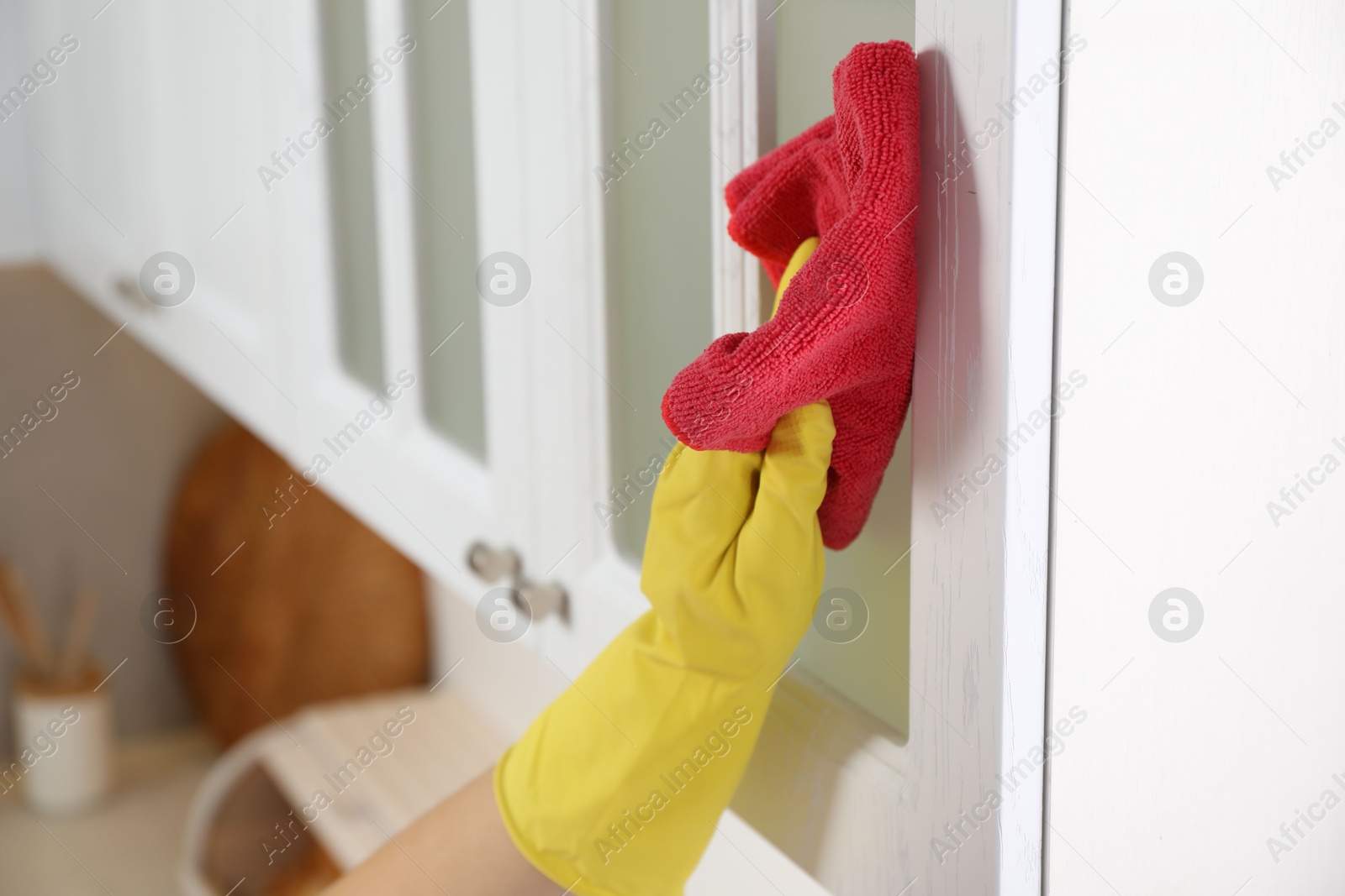 Photo of Woman cleaning furniture with rag in kitchen, closeup