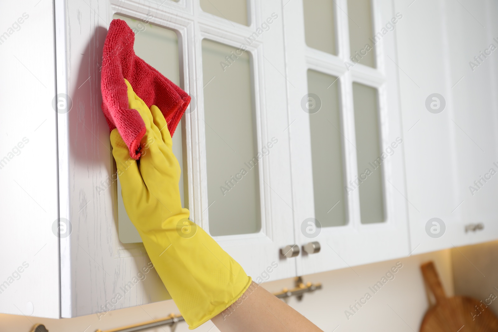 Photo of Woman cleaning furniture with rag in kitchen, closeup