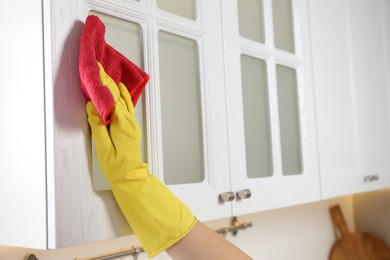 Woman cleaning furniture with rag in kitchen, closeup