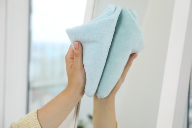 Photo of Woman cleaning mirror with rag indoors, closeup