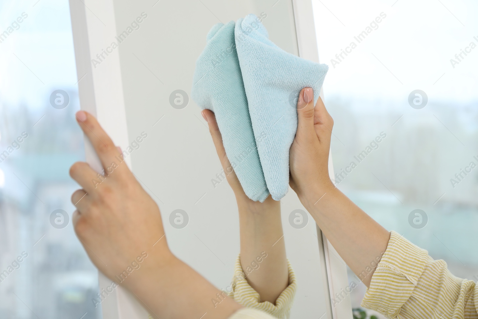 Photo of Woman cleaning mirror with rag indoors, closeup