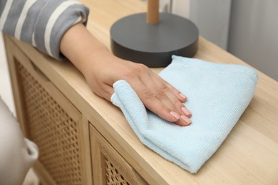 Woman wiping furniture with rag indoors, closeup