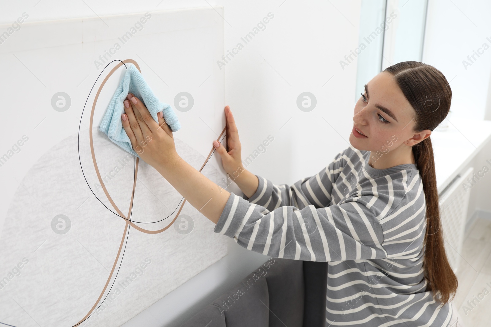 Photo of Beautiful young woman wiping picture with rag at home