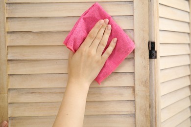 Woman wiping folding screen with rag indoors, closeup