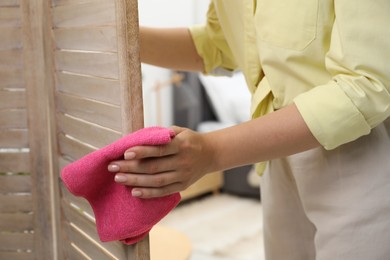 Woman wiping folding screen with rag indoors, closeup