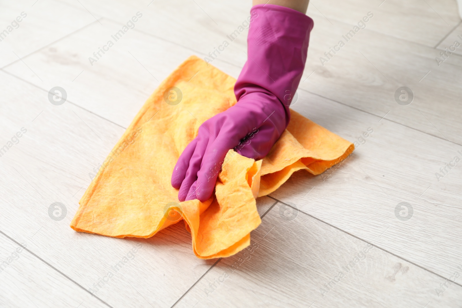 Photo of Woman in glove cleaning floor with rag, closeup