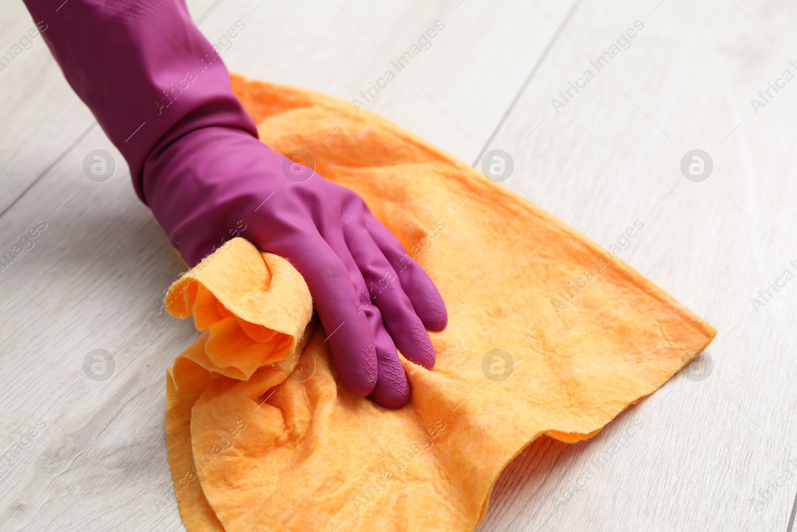 Photo of Woman in glove cleaning floor with rag, closeup