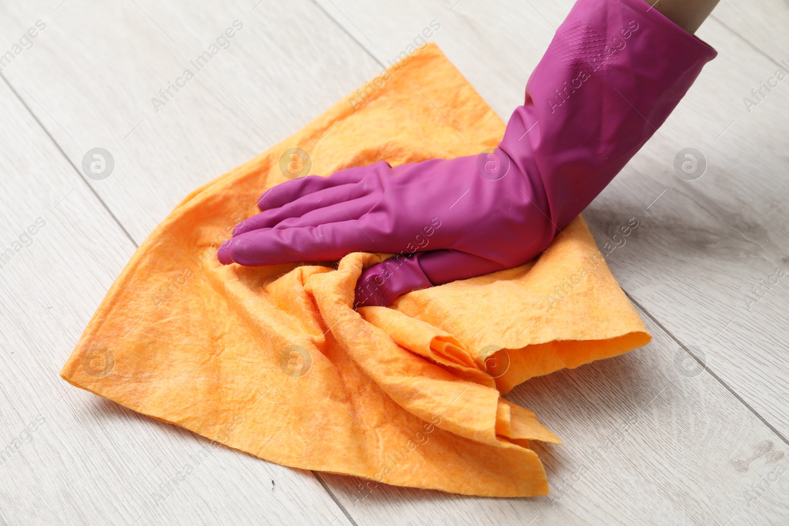 Photo of Woman in glove cleaning floor with rag, closeup