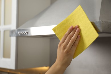 Photo of Woman cleaning kitchen hood with napkin at home, closeup