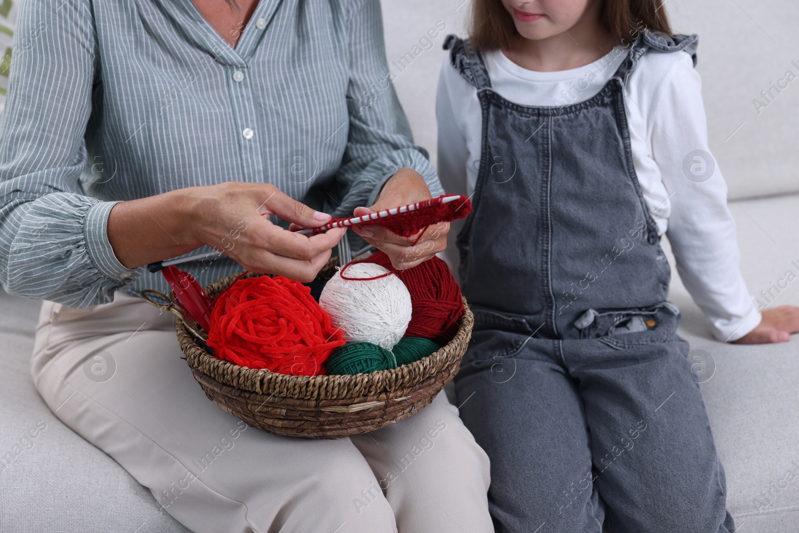 Photo of Grandmother teaching her granddaughter to knit at home, closeup