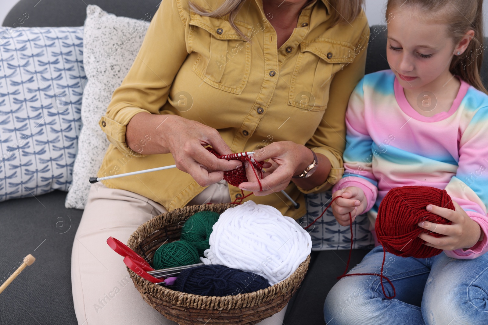 Photo of Grandmother teaching her granddaughter to knit at home, closeup