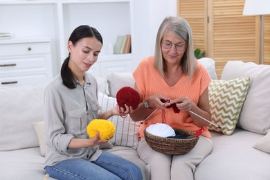 Photo of Mother and daughter with skeins of yarn spending time together at home