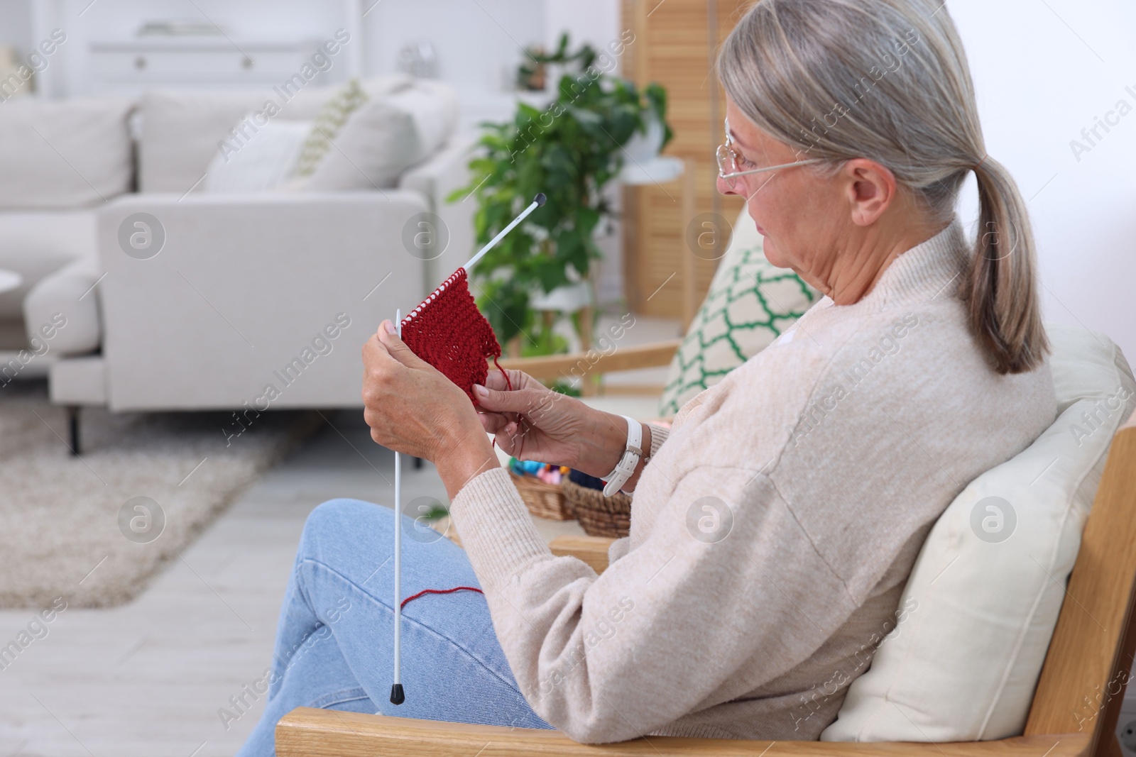 Photo of Senior woman with knitting needles looking at pattern at home