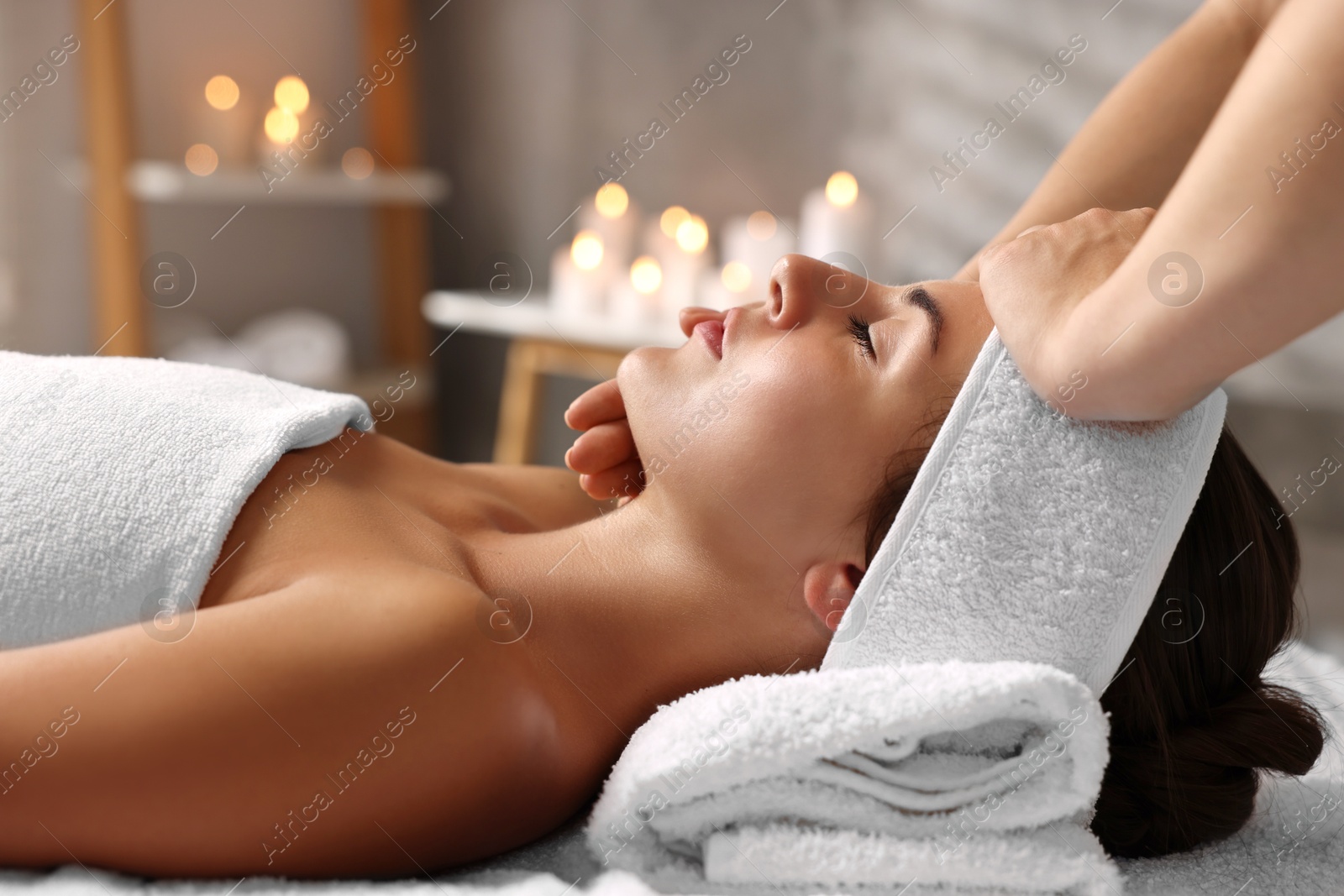 Photo of Attractive woman enjoying face massage in spa salon, closeup