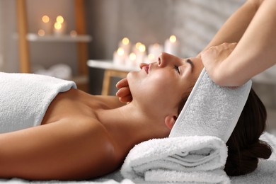 Photo of Attractive woman enjoying face massage in spa salon, closeup