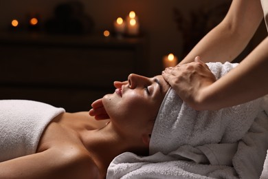 Attractive woman enjoying face massage in spa salon, closeup