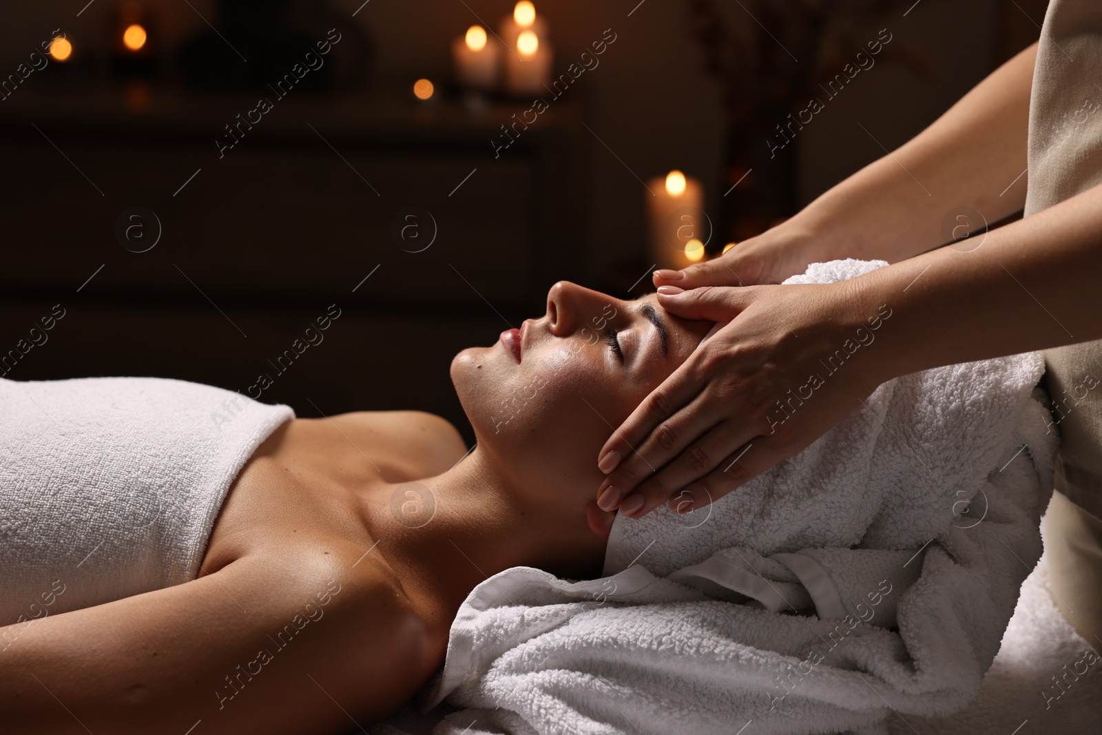 Photo of Attractive woman enjoying face massage in spa salon, closeup