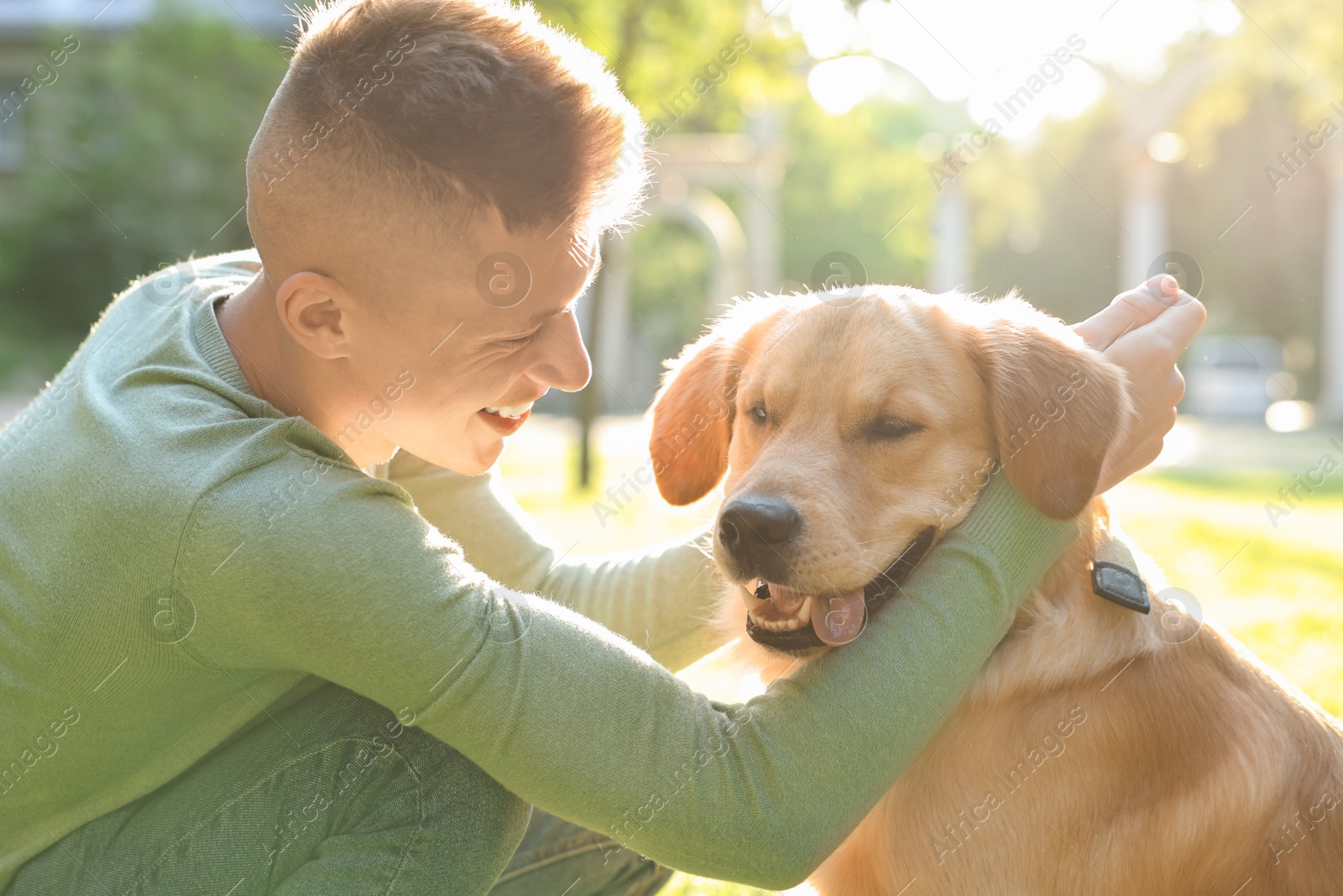 Photo of Young man with his lovely dog in park on sunny day